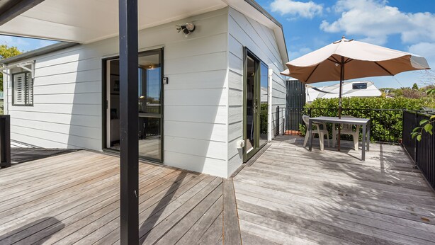 A modern house with a wooden deck, a covered patio, and a table with chairs. - Casa Verde - Mapua Holiday Home (Mapua)