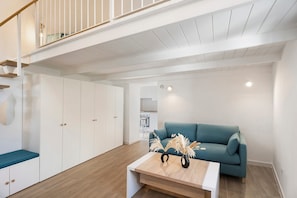 A modern interior with a staircase, white wardrobe, teal sofa, and a wooden coffee table. - La Casa Quattrocchi – Tradition and Modern Comfort in Testaccio (Barano D'ischia)