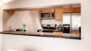 A modern kitchen with stainless steel appliances, wooden cabinets, and a black countertop. - Global Luxury Suites in Abilene Texas (Abilene)