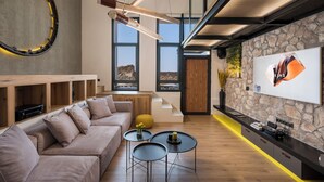 Un salon moderne avec un canapé, des tables basses et un téléviseur fixé au mur, qui est en pierre.