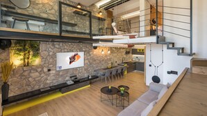 Un intérieur moderne avec un mur en pierre, un coin repas, une cuisine et un escalier.