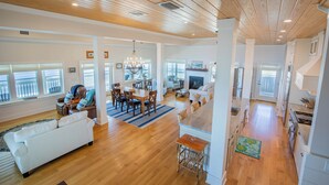 A spacious living area with a wooden ceiling, a dining area, and a kitchen. - Luxury, old-Florida charm, N. Cape gulf front, outdoor TV, pvt beach access (Port Saint Joe, FL)