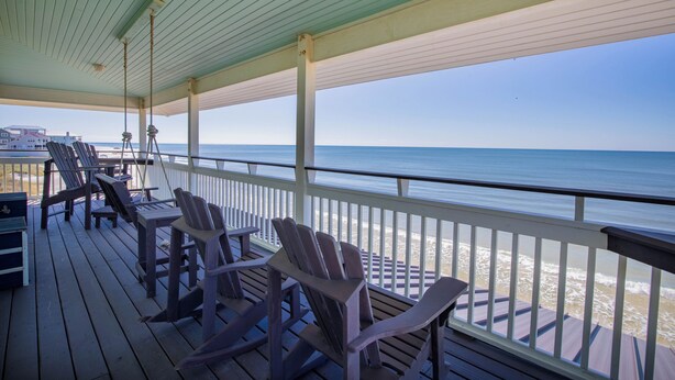 A wooden deck with Adirondack chairs and a table, overlooking a beach and ocean. - Luxury, old-Florida charm, N. Cape gulf front, outdoor TV, pvt beach access (Port Saint Joe, FL)
