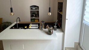 A modern kitchen with a central island, pendant lighting, and exposed brick walls. - [Casa Camelia] Elegant Palace with Terrace (Conversano)