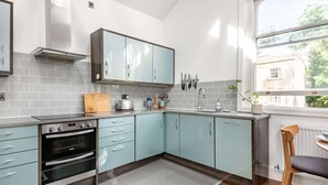 A modern kitchen with light blue cabinets, a stainless steel oven, and a window providing a view of the outside. - Two bedroom loft in central Bristol (City of Bristol)