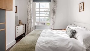 A bedroom with a bed, a dresser, a window with curtains, and a framed picture on the wall. - Two bedroom loft in central Bristol (City of Bristol)