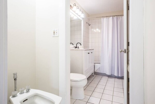 Un baño con inodoro, lavamanos y zona de ducha.