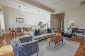 Una sala de estar amplia con sofá, sillones, una mesa de centro y un comedor con sillas y una mesa.