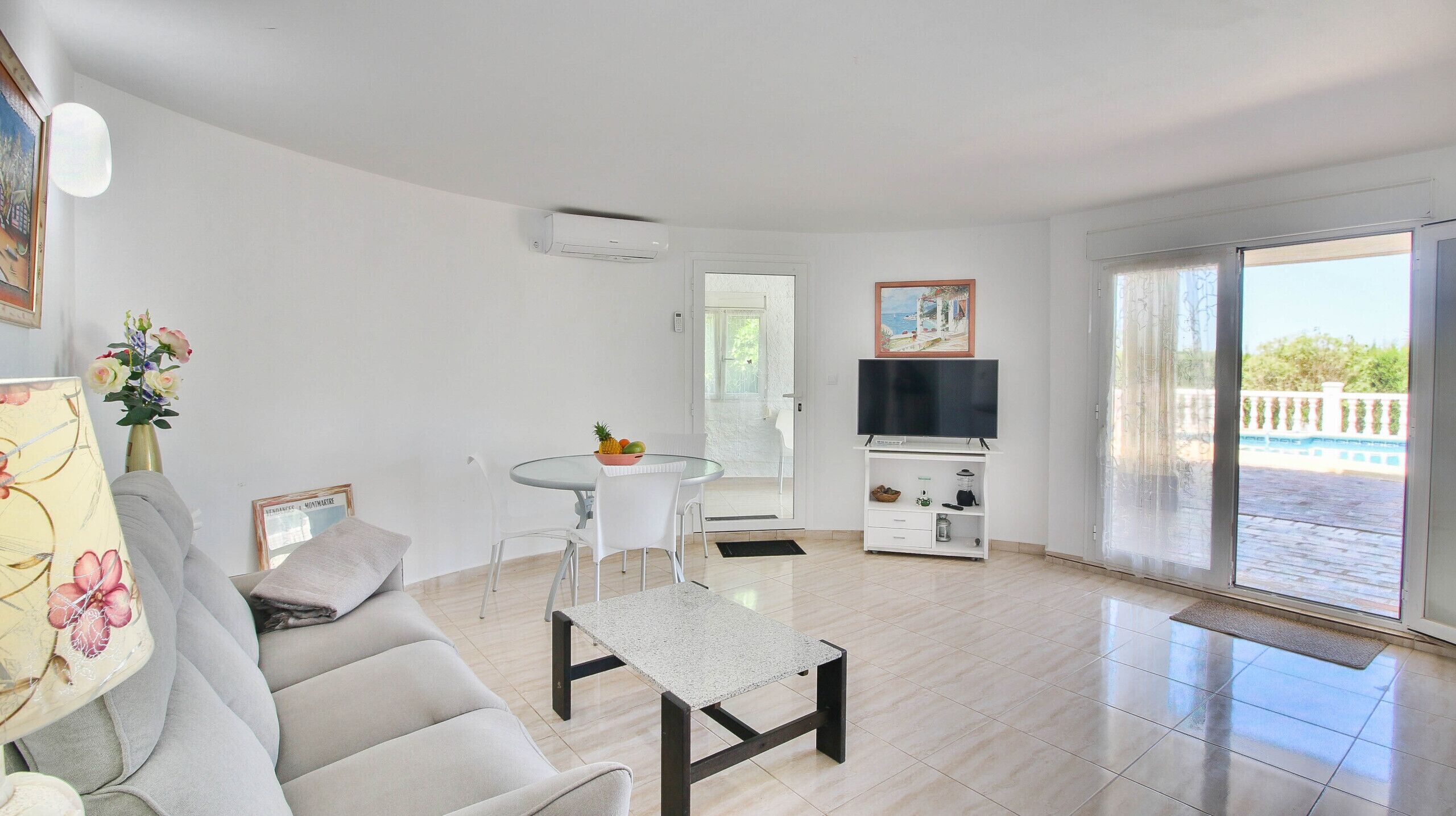 A modern living room with a sofa, a coffee table, a TV, and a dining area with a table and chairs.