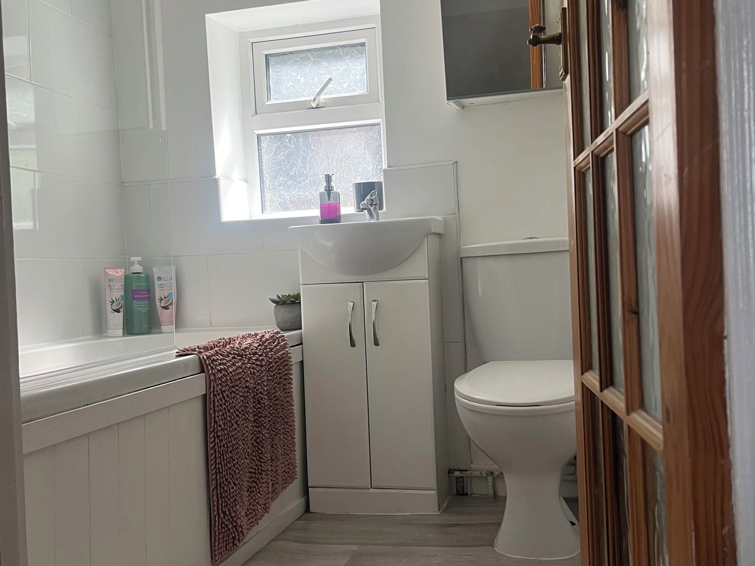 A bathroom with a white sink, a toilet, and a window above the sink.
