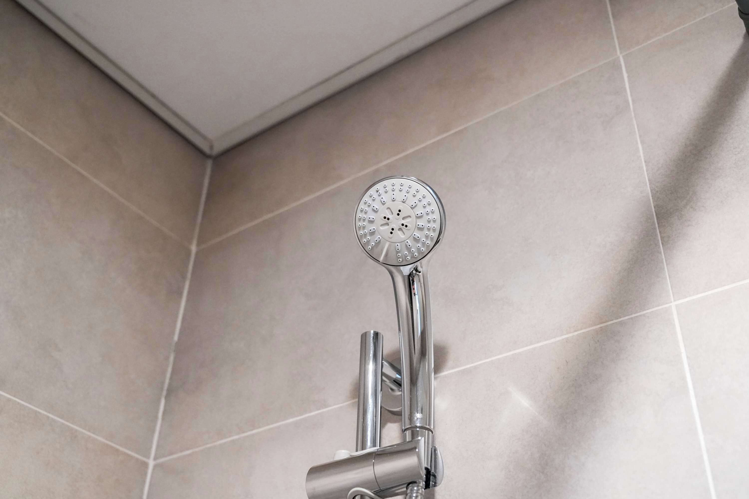 Chuveiro moderno com design circular, fixado em um acessório cromado.