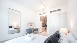 A modern hotel room with a large bed, a desk, and a wardrobe. - StayShort - Studio in Damac Hills that Sleeps 3 with Terrace! (Damac Hills)