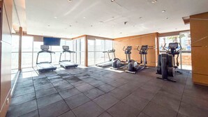 A modern gym with treadmills, elliptical machines, and a large window providing natural light. - StayShort - Studio in Damac Hills that Sleeps 3 with Terrace! (Damac Hills)