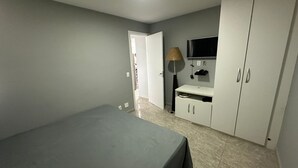 Une chambre à coucher avec un lit, une armoire, une télévision et une lampe.