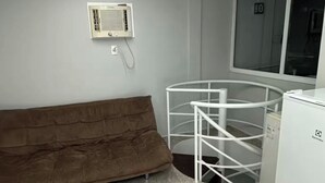 Une pièce moderne avec un canapé marron, un radiateur blanc, une structure circulaire blanche et un appareil électroménager blanc.