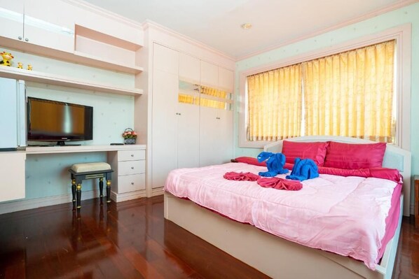 A bedroom with a bed, a TV, and a desk.