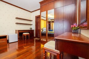 Una habitación con suelo de madera, un escritorio, una silla, un armario y una cama con un espejo.