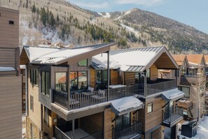 Un immeuble à plusieurs étages doté de balcons, de grandes fenêtres et offrant une vue sur une montagne enneigée.