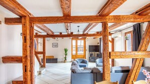 Un intérieur rustique avec des poutres apparentes, un sol carrelé, un canapé, une table et un téléviseur.