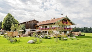 A large house with a spacious lawn, a wooden deck, and a dining area. - Hussnhof Farm Lodge (Sachsenkam)