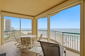 A balcony with a table and chairs, overlooking a beach and ocean. - NEW LISTING!!! Beach Colony West 6B- Gulf Front with Indoor Pool! (Pensacola)
