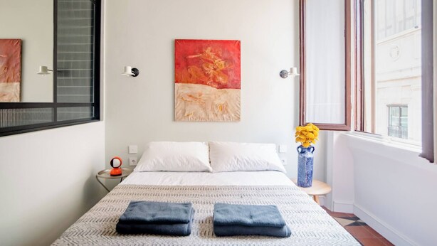 A bedroom with a bed, a painting, a vase with flowers, and a window. - Room-central Design Room - Private Bathr (Milan)