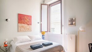 A bedroom with a bed, a window, a radiator, and a vase with flowers. - Room-central Design Room - Private Bathr (Milan)