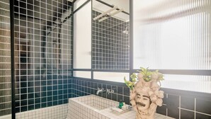 A bathroom with a bathtub, a sink with a decorative vase, and a large mirror. - Room-central Design Room - Private Bathr (Milan)