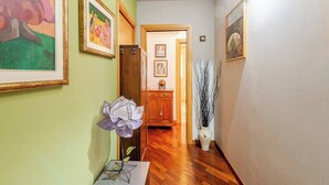 Un pasillo con piso de madera, paredes verdes y varias obras de arte enmarcadas.