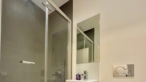 Un baño moderno con cabina de ducha de vidrio, lavabo blanco y inodoro.