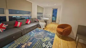 Una sala de estar moderna con un sofá gris, un tapete estampado y suelo de madera.