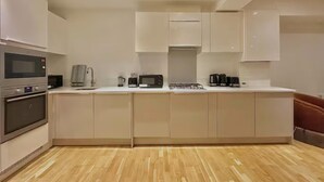 Una cocina moderna con armarios blancos, microondas, cafetera y tostadora.