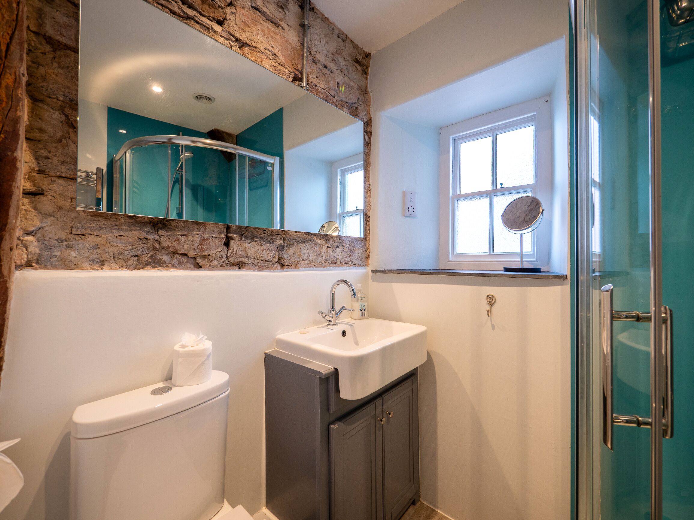 Ein Badezimmer mit Toilette, Waschbecken, Spiegel und Dusche.