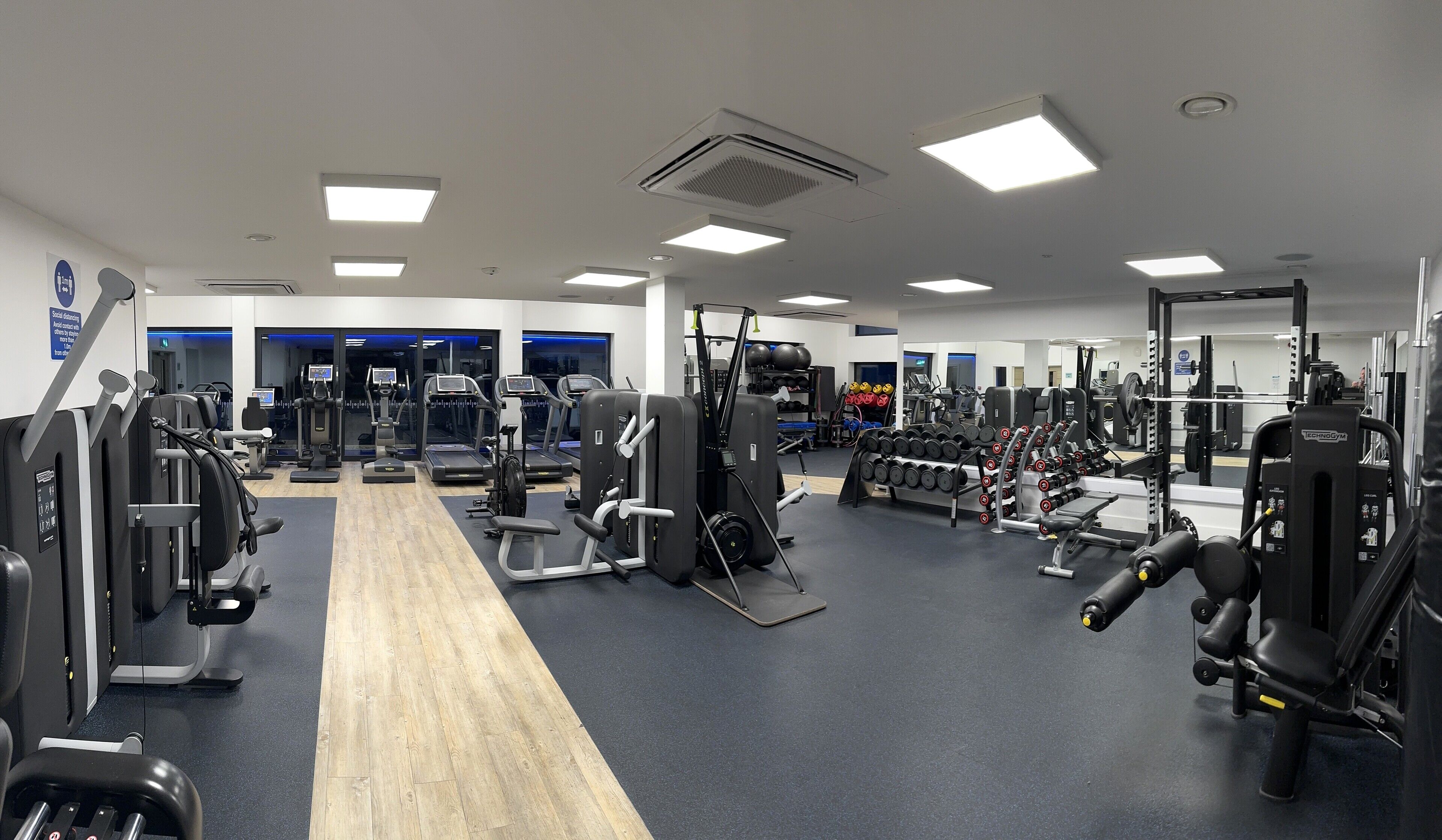 A gym with cardio machines, weightlifting equipment, and a mirror wall.