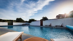 A swimming pool with lounge chairs and a wooden table. - Landal Whalesborough (Bude)