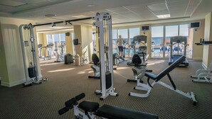 A gym with various exercise equipment, large windows, and a view of the ocean. - Beachfront Condo w/ Free Beach Service Near Pier Park (Panama City Beach)