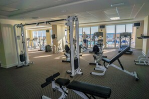 A gym with various exercise equipment, large windows, and a view of the ocean. - Beachfront Condo w/ Free Beach Service Near Pier Park (Panama City Beach)