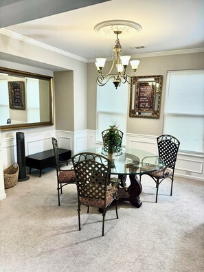 A dining room with a glass table surrounded by four chairs, a chandelier, a large mirror, and two framed inspirational quotes on the wall. - Luxury Furnished 4BR with Loft in the City of South Fulton Near Atlanta Airport (Atlanta)