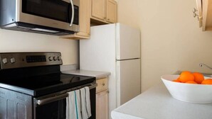 A kitchen with a microwave, oven, and refrigerator. There is a bowl of oranges on the counter. - Beautiful 1BR near Fenway Park + Kenmore! (Boston)