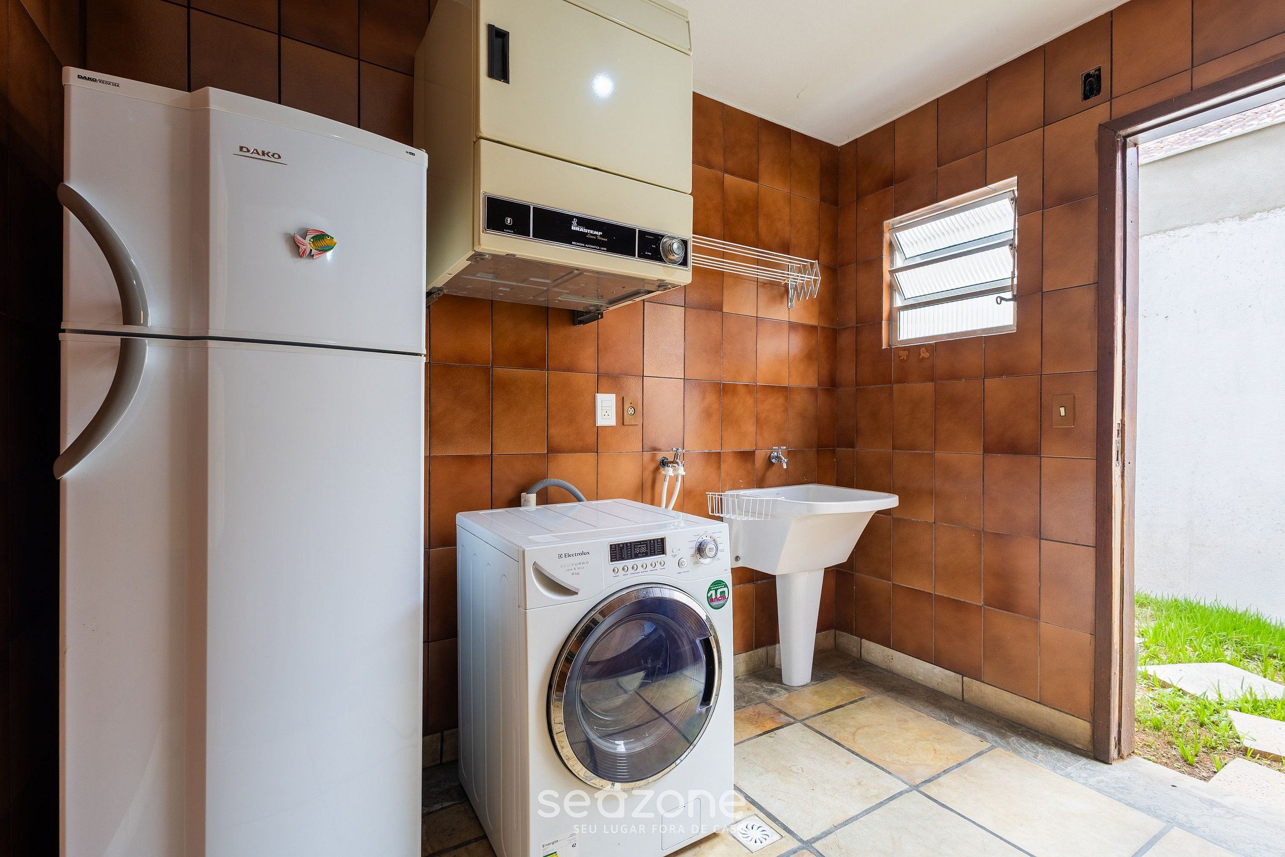 A compact kitchen with a refrigerator, washing machine, and sink.
