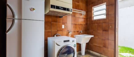 Una cocina funcional con refrigerador, lavadora y pileta.