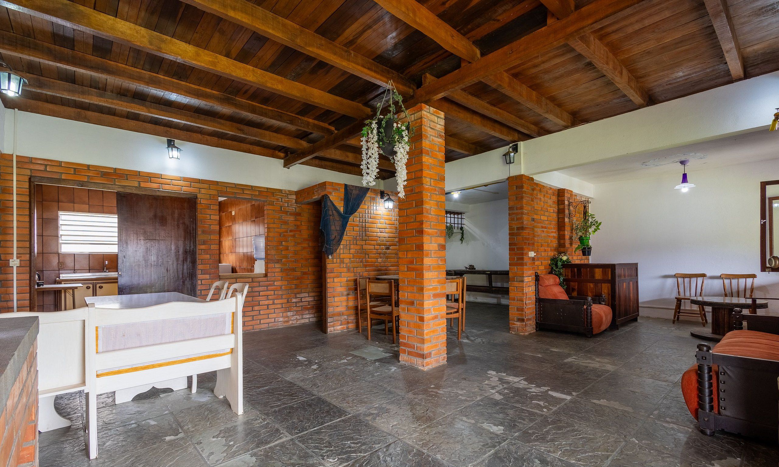 A spacious room with exposed wooden beams, a brick wall, and a bed with a white headboard.
