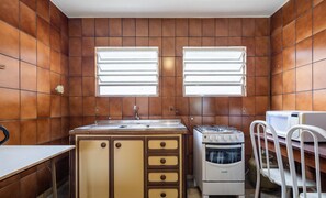 A compact kitchen with a sink, stove, and two windows. - Large 3-bedroom House in Penha Sel0068 (Penha)