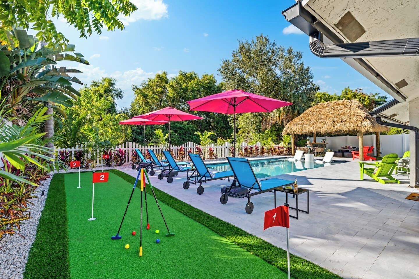 A poolside area with lounge chairs, a croquet set, and a thatched umbrella.