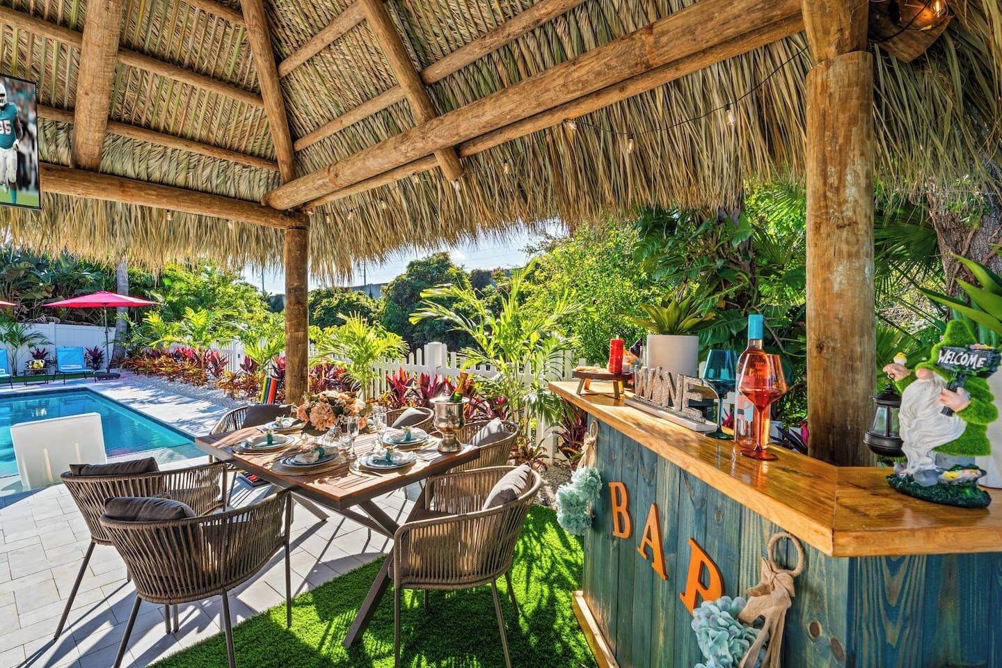 An outdoor bar area with a pool, wicker chairs, and a thatched roof.