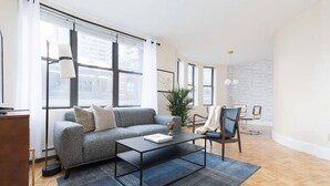 A modern living room with a grey sofa, a black coffee table, and a wooden floor. - Walking distance to Beacon Hill, Back Bay + all tourist spots.  Great for work trip too, MBTA nearby (Boston)