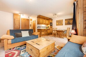 Ein gemütliches Wohnzimmer mit einer Couch, einem Holztisch und einem Essbereich mit Tisch und Stühlen.