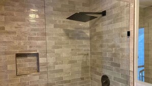 A shower with a glass door and a rain showerhead. - Newly Renovated 3 Bedroom! Walk to Bars and Restaurants (Killington)