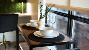 Una mesa de comedor con cuencos y platos blancos, un florero con planta, y copas de vino.