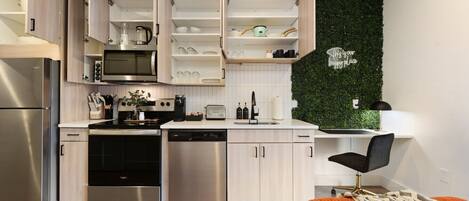 Une cuisine moderne dotée d’appareils électroménagers intégrés, d’étagères ouvertes et d’un mur végétal.